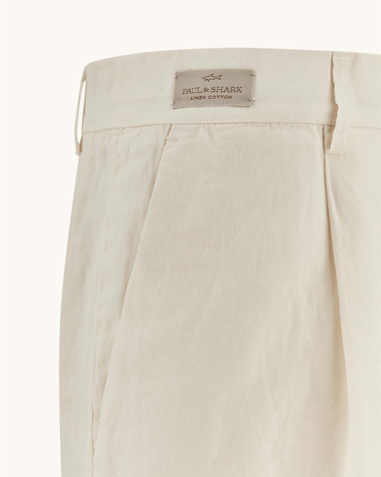 Detaljbilde av modell som hodler en hånd i bukselommen. Lomme bak og beltehemper i fokus