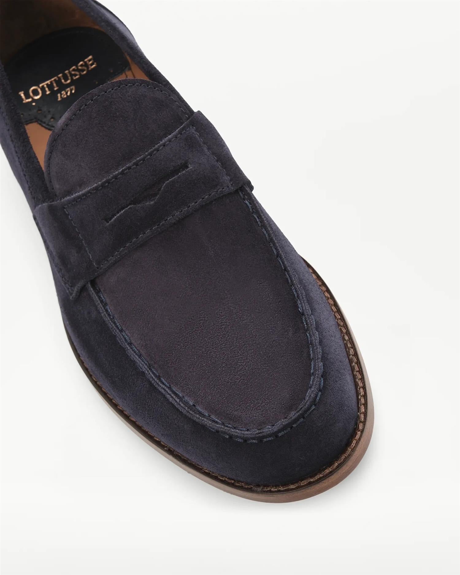 Detaljbilde av navy semsket Lottusse loafers som viser penny-strap, håndsydde sømmer og struktur i kalveskinn.