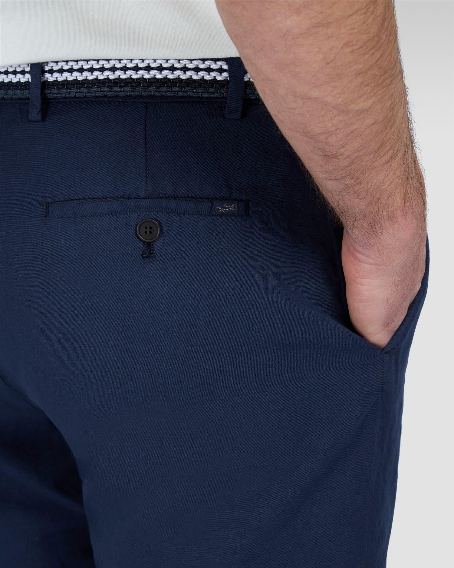 Detaljbilde av modell som hodler en hånd i bukselommen. Lomme bak og beltehemper i fokus